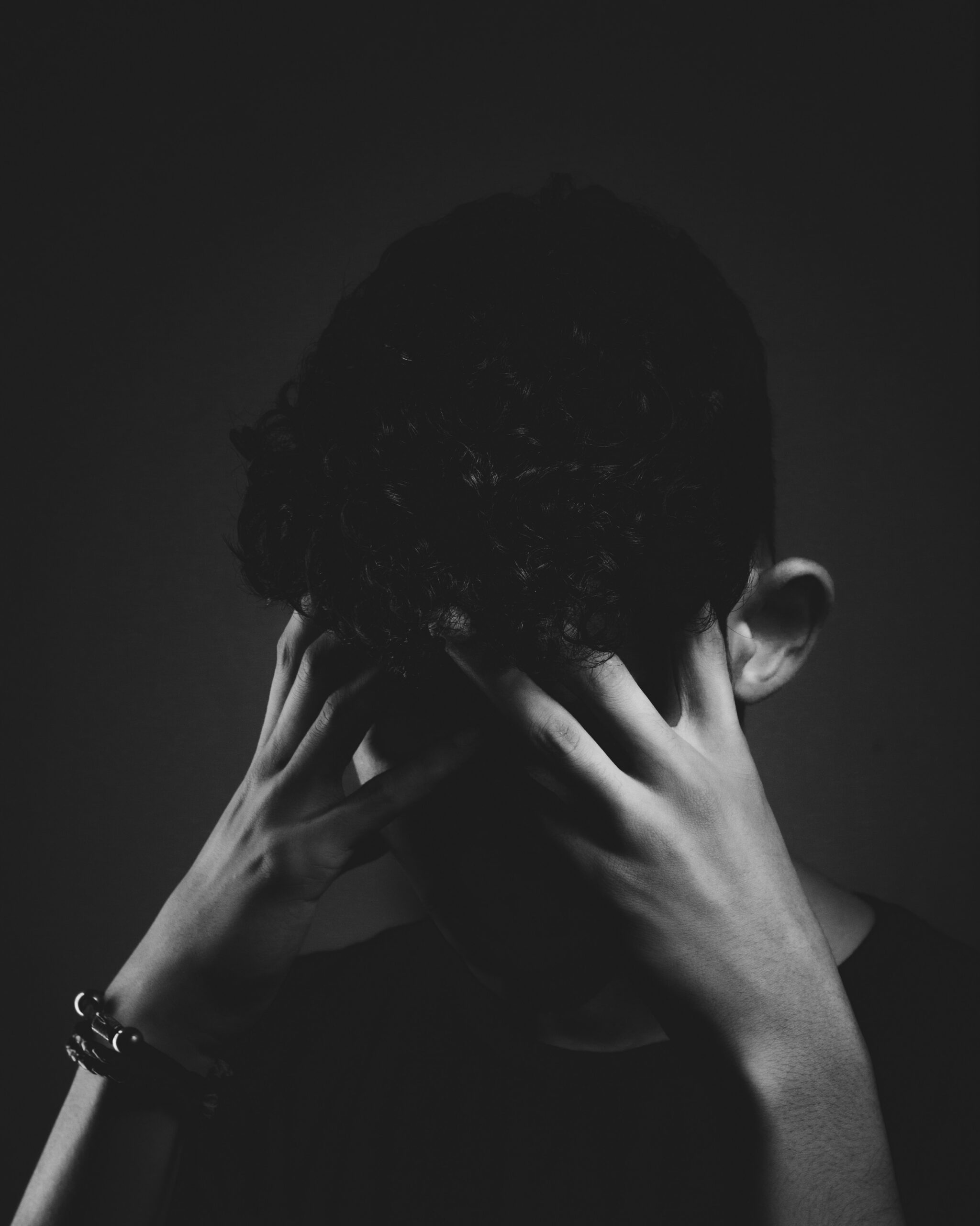 "Man holding his head in darkness, symbolizing mental stress, anxiety, and emotional overwhelm."