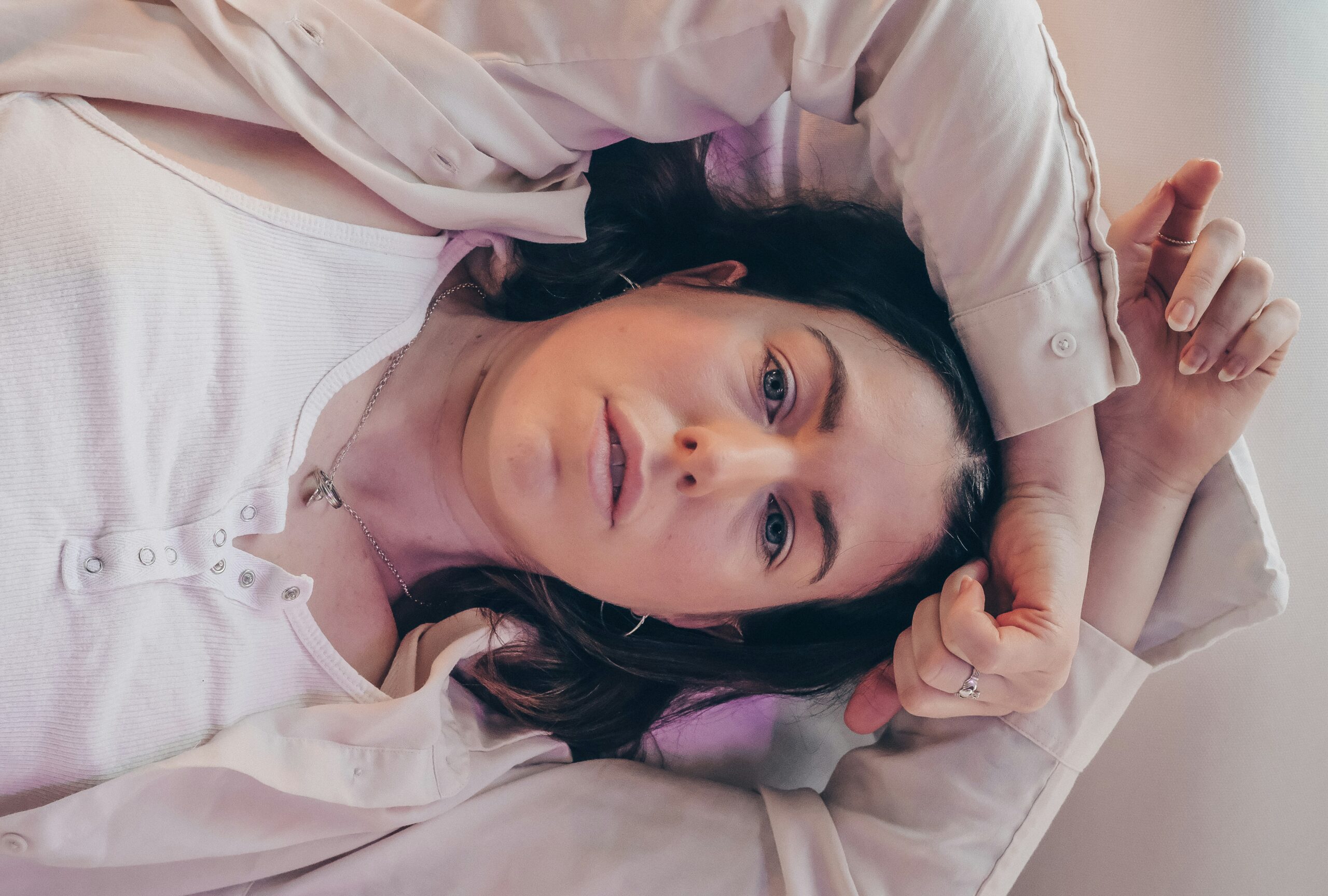 A young woman lying on a bed with a blank expression, symbolizing emotional exhaustion and hidden anxiety symptoms.
