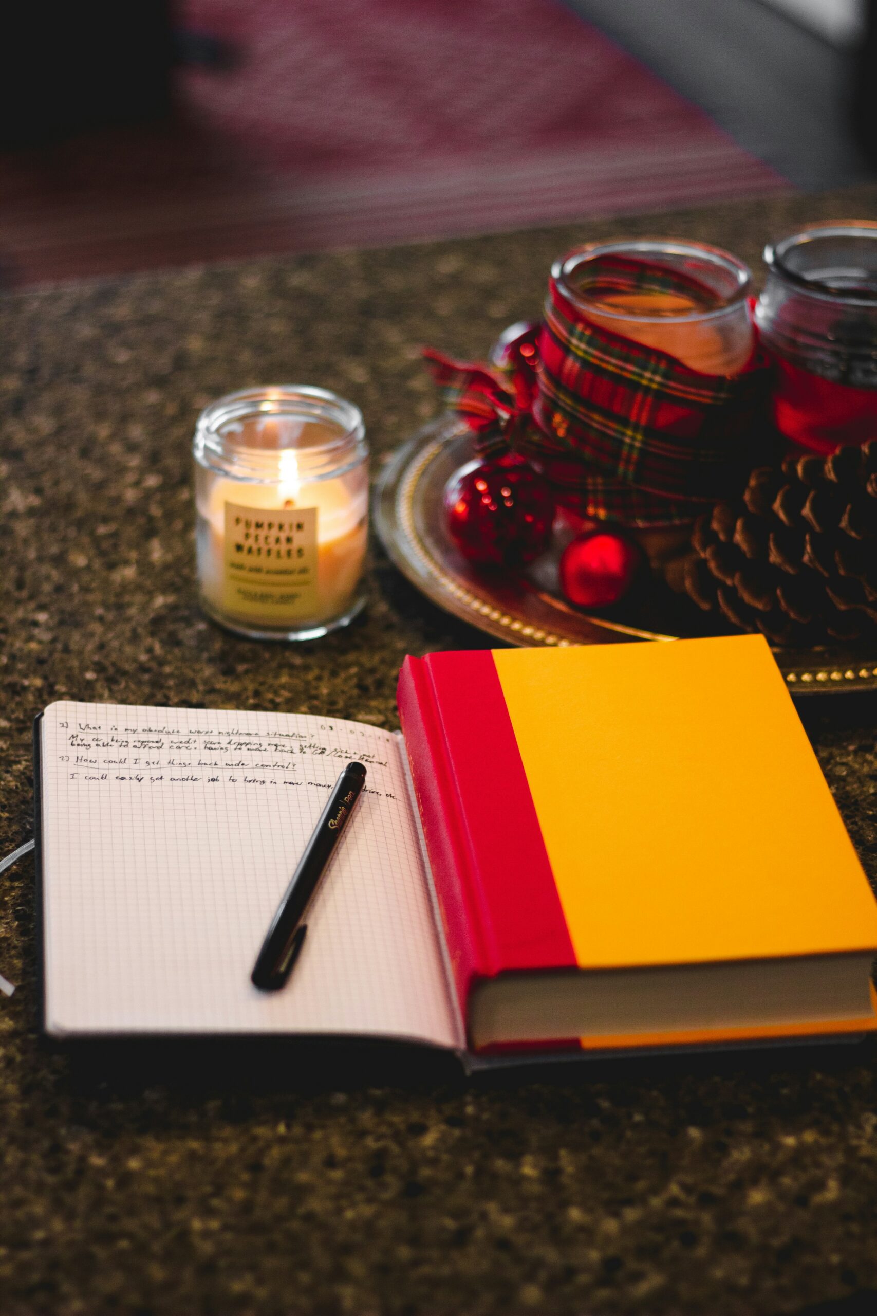 A cozy journal with a pen and a lit candle on a warm table setup, symbolizing healing, self-reflection, and the journey through anxiety recovery.