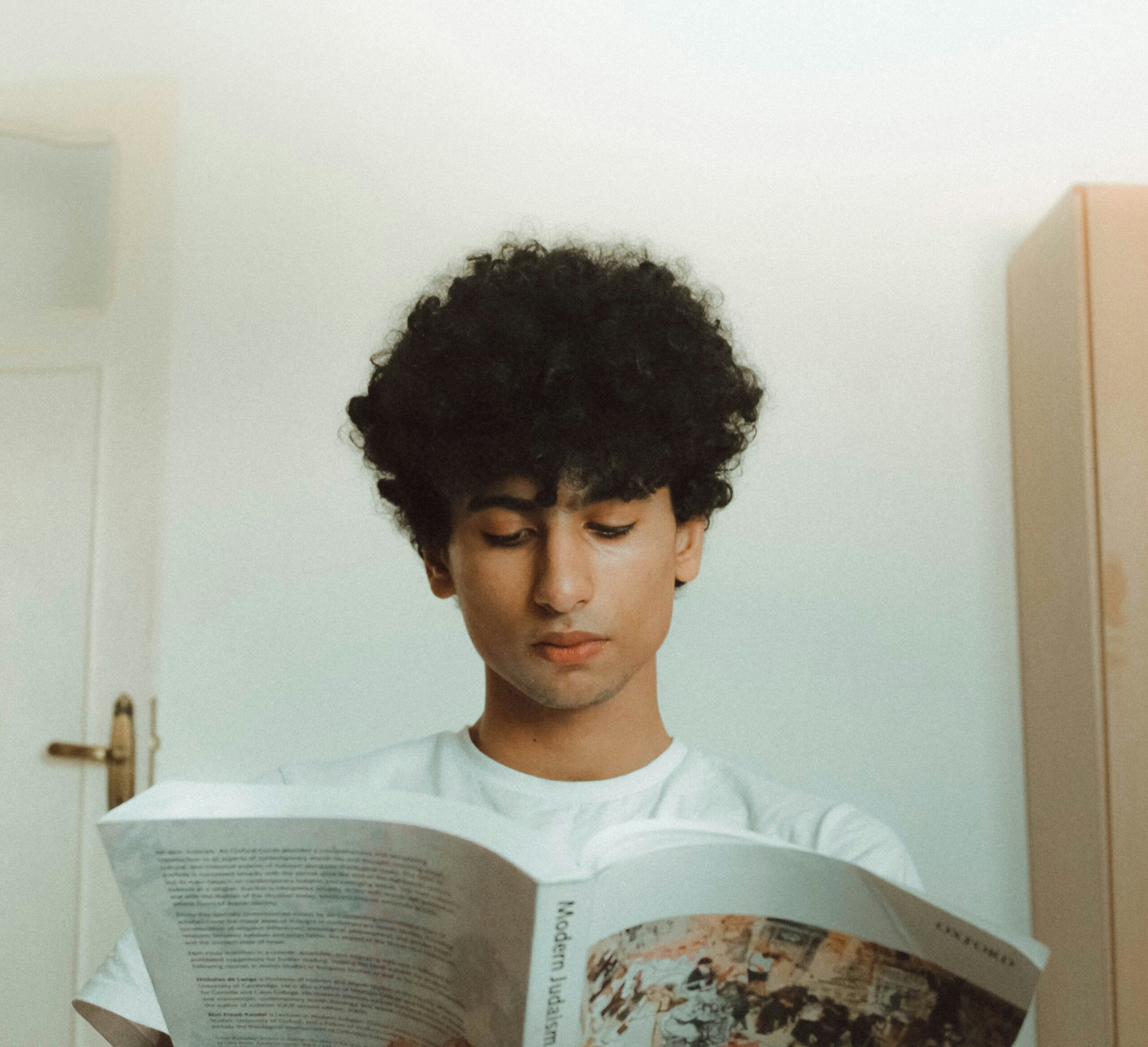 Young man reading a book alone in a quiet room, symbolizing focus and healing from anxiety.