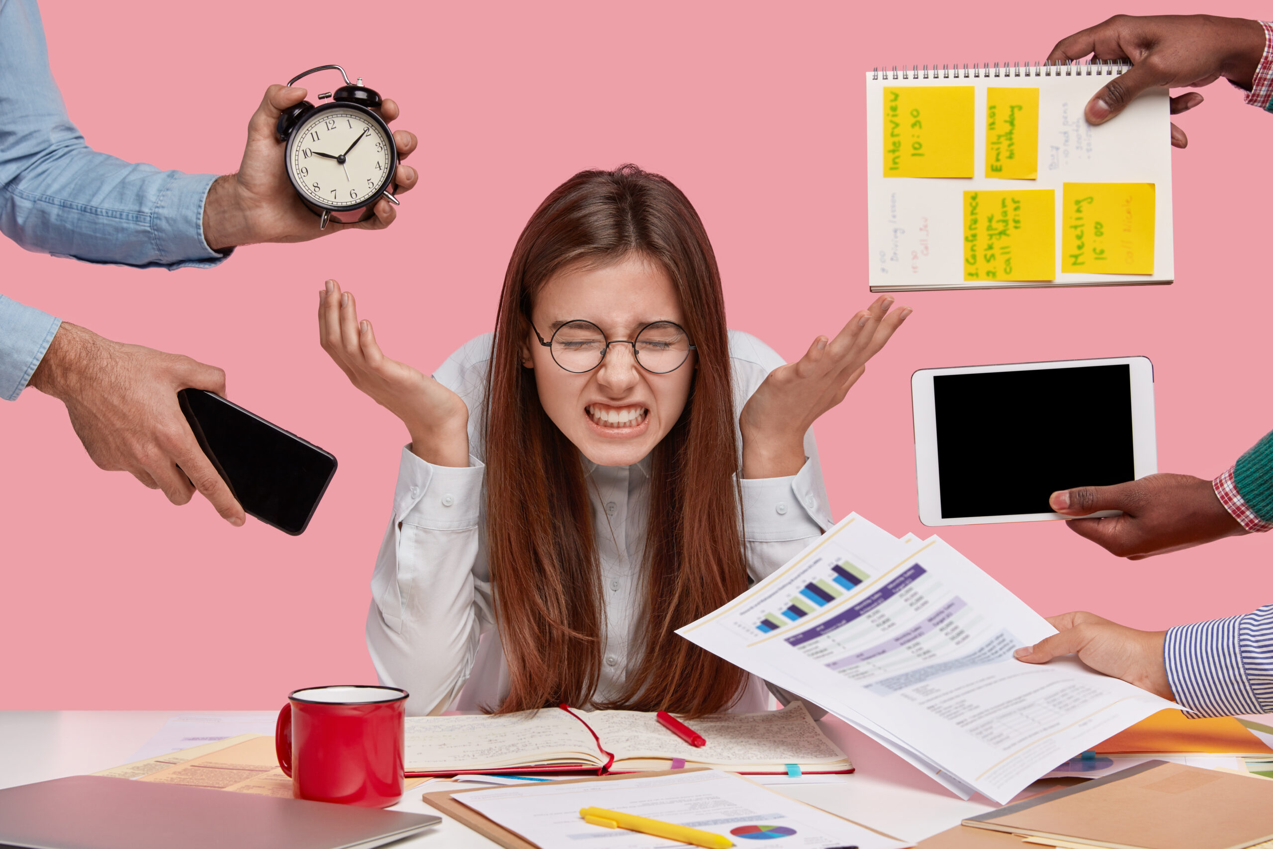 "Stressed young woman sitting at desk surrounded by clock, phone, documents, tablet, and sticky notes, feeling pressure from workload and deadlines."